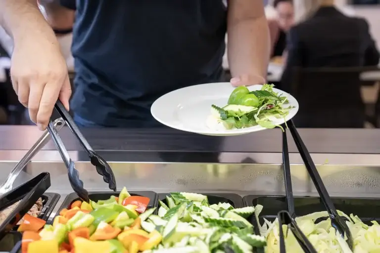 Person som forsyner seg med salat i Løvetann Kantine