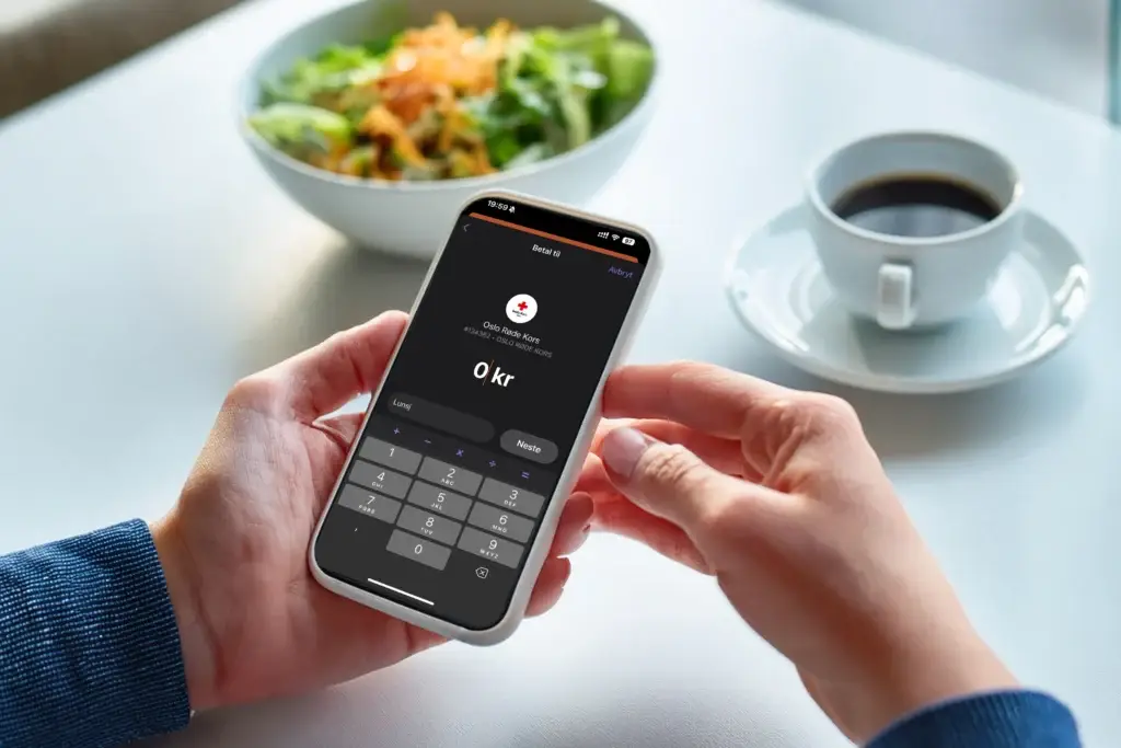 Hender som holder i en mobil for å betale med Vipps.