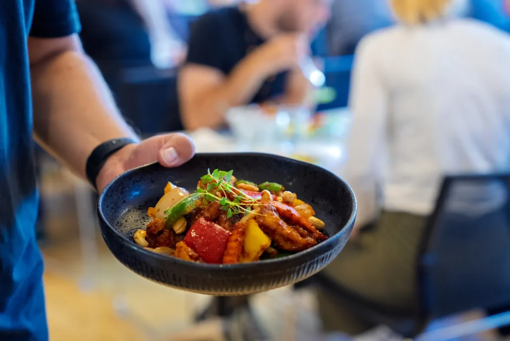 Person som holder en tallerken med mat i en kantine